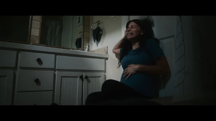 A pregnant woman crying on a bathroom floor